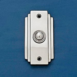 Può includere: Un pulsante di campanello rettangolare bianco con un pulsante cromato al centro. Il campanello ha un design Art Déco decorativo.