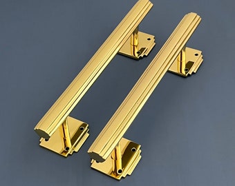 Könnte beinhalten: Zwei goldene Türklinken im Art-Deco-Stil. Die Griffe sind aus massivem Messing gefertigt und haben eine polierte Oberfläche.