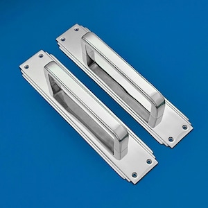 Peut inclure: Deux poignées de porte en chrome poli avec une plaque rectangulaire et une poignée encastrée. Les poignées ont un design moderne Art déco.
