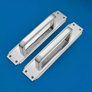 May include: Two polished chrome door handles with a rectangular shape and a recessed handle. The handles have a decorative Art Deco design.