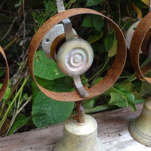 May include: Three antique brass doorbells with rusty metal frames. The doorbells are mounted on a wooden surface. Each doorbell has a round, decorative brass bell and a lever.