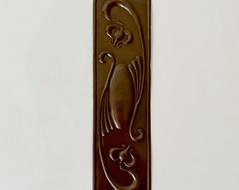 May include: A brown metal door plate with an Art Nouveau design featuring stylised flowers and leaves.