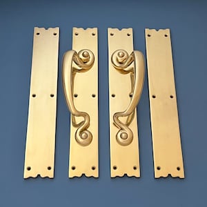 Puede incluir: Cuatro tiradores de puerta de latón con un diseño decorativo y ornamentado. Los tiradores son rectangulares y tienen un diseño curvo y estilizado.
