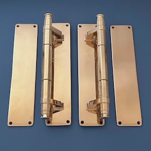 Puede incluir: Dos manillas de puerta doradas con placas rectangulares a juego. Las manillas son de metal y tienen un acabado pulido.