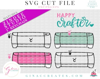 May include: A digital cutting machine with the text "Happy Crafter" in pink and teal lettering. The machine is shown in three different colors: white, teal, and pink. The image also includes the text "Matches Zindee Studio 3" Keychain".