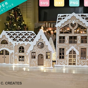 May include: Three white and brown gingerbread house paper cut files. The houses have intricate details and are decorated with white frosting. The text "PAPER SVG CUT FILE" is in the top left corner of the image.