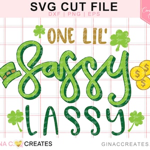 May include: Green and gold SVG cut file design that says "One Lil' Sassy Lass" with shamrocks and a leprechaun hat.