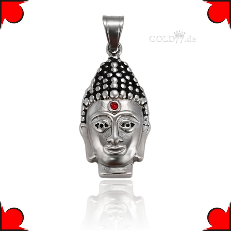 Puede incluir: Colgante de plata con una cabeza de Buda detallada con una piedra preciosa roja en el centro de la frente. El colgante tiene un dise&ntilde;o texturizado en negro y plata.