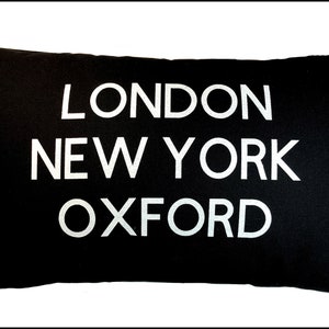 Può includere: Cuscino nero con testo bianco che dice "LONDON NEW YORK OXFORD"