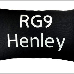 Może przedstawiać: Czarna prostokątna poduszka z białym tekstem, który brzmi "RG9 Henley".