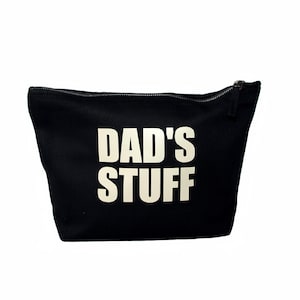 Puede incluir: Bolsa de lona negra con cremallera y texto blanco que dice "DAD'S STUFF".