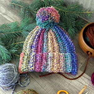 Gorro de canalé morado, verde azulado, naranja y amarillo con pompón