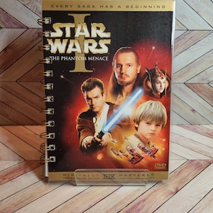 May include: A Star Wars Episode I: The Phantom Menace DVD cover featuring a red background with a lightsaber and characters from the movie. The text "EVERY SAGA HAS A BEGINNING" is at the top of the cover. The DVD is digitally mastered for superior sound and picture quality.