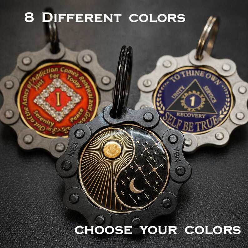 May include: Three circular metal keychains with bicycle chain borders. One features a red center with a diamond and text, one a blue center with a triangle and text, and one a black yin-yang design with a sun and moon. Text: 8 DIFFERENT COLORS CHOOSE YOUR COLORS.