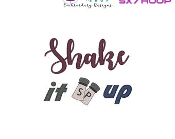 Puede incluir: Diseño de bordado para un aro de 5x7 cm con el texto "Shake it up" y un gráfico de salero y pimentero. El texto está en color marrón y los saleros y pimenteros están en gris.
