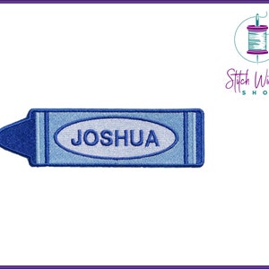 K&ouml;nnte beinhalten: Blauer gestickter B&uuml;geleisen-Aufn&auml;her in Form eines Buntstiftes mit dem Namen "JOSHUA" in wei&szlig;en Buchstaben.