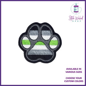 May include: A gray, white, and green paw print embroidered patch. The paw print is in the style of the ace flag, with green stripes on the top and bottom and a white stripe in the middle. The patch is available in various sizes and custom colors.