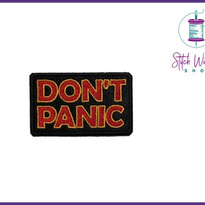 Könnte beinhalten: Schwarzer gestickter Aufnäher mit roter und gelber Aufschrift "DON'T PANIC".
