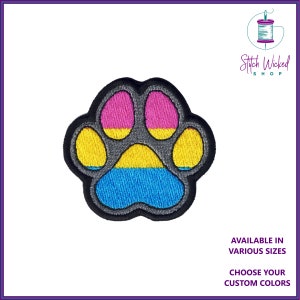 Könnte beinhalten: Gestickter Pfotenabdruck-Patch in den Farben der pansexuellen Pride-Flagge: Pink, Gelb und Blau. Das Logo von Stitch Wicked Shop befindet sich oben rechts. Erhältlich in verschiedenen Größen und Farben.