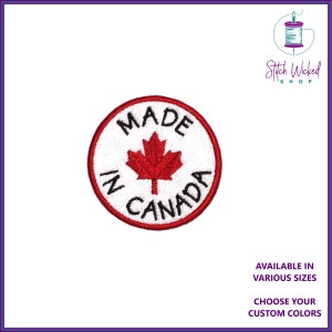 Può includere: Una toppa rotonda, bianca e ricamata con una foglia d'acero rossa al centro. Il testo "MADE IN CANADA" è scritto in nero attorno alla foglia. La toppa ha un bordo rosso.