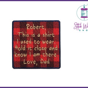 May include: An embroidered patch with a red and black check design. The patch has the text "Robert, This is a shirt I used to wear. Hold it close and know I am there. Love, Dad" in gold thread. The patch is square with a navy blue border.