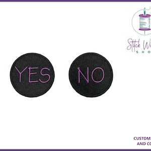 Könnte beinhalten: Zwei schwarze, kreisförmige Aufnäher mit gesticktem Text. Ein Aufnäher zeigt "YES" in Lila, der andere "NO" in Lila. Die Aufnäher sind wahrscheinlich für Kleidung oder Accessoires.