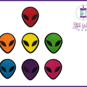 May include: Set of eight embroidered iron-on patches featuring alien faces in various colours: red, orange, yellow, green, blue, purple, pink, and black.