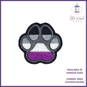 May include: An embroidered patch featuring an asexual pride flag paw print. The patch is grey, white and purple. Stitch Wicked Shop.