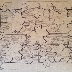 May include: A black and white line drawing of maple leaves on a beige linen fabric. The leaves are arranged in a symmetrical pattern, with four large leaves in the center and smaller leaves around the edges.