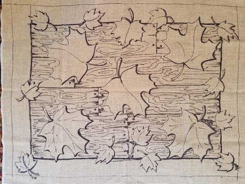 May include: A black and white line drawing of maple leaves on a beige linen fabric. The leaves are arranged in a symmetrical pattern, with four large leaves in the center and smaller leaves around the edges.