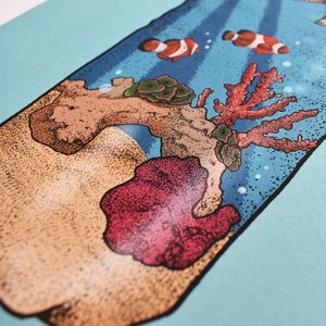 May include: A close-up of a glass bottle with a cork stopper. The bottle is filled with sand and coral, and there are two small orange and white fish swimming inside. The bottle is on a light blue background.