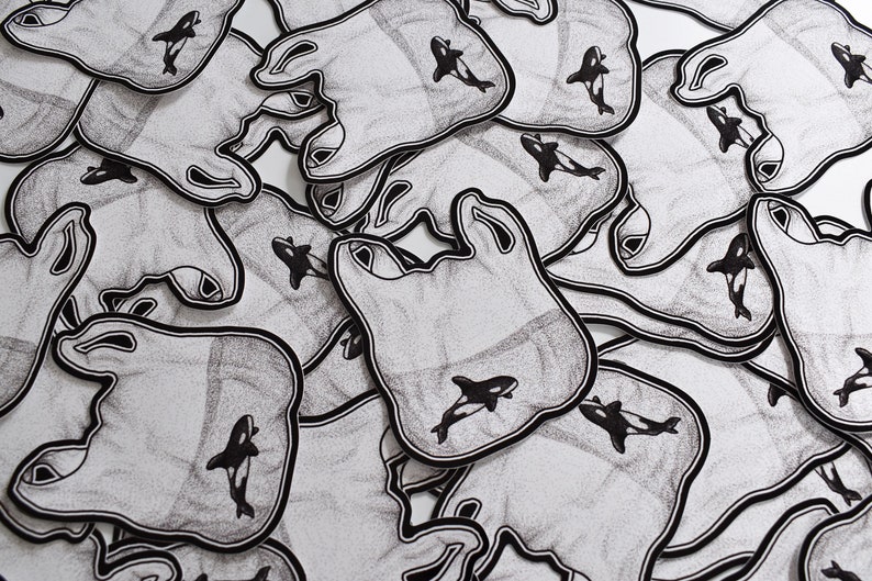 May include: A pile of black and white stickers with a graphic of a plastic bag and an orca whale. The stickers are printed on a white background.