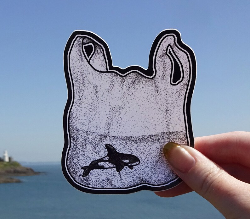 May include: A black and white illustration of a plastic bag with a small orca whale inside. The bag is drawn in a cartoon style and has a white background.