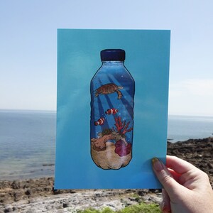 May include: A blue plastic bottle with a sea turtle, coral, and clownfish inside. The bottle is on a blue background. The image is a reminder of the impact of plastic pollution on marine life.