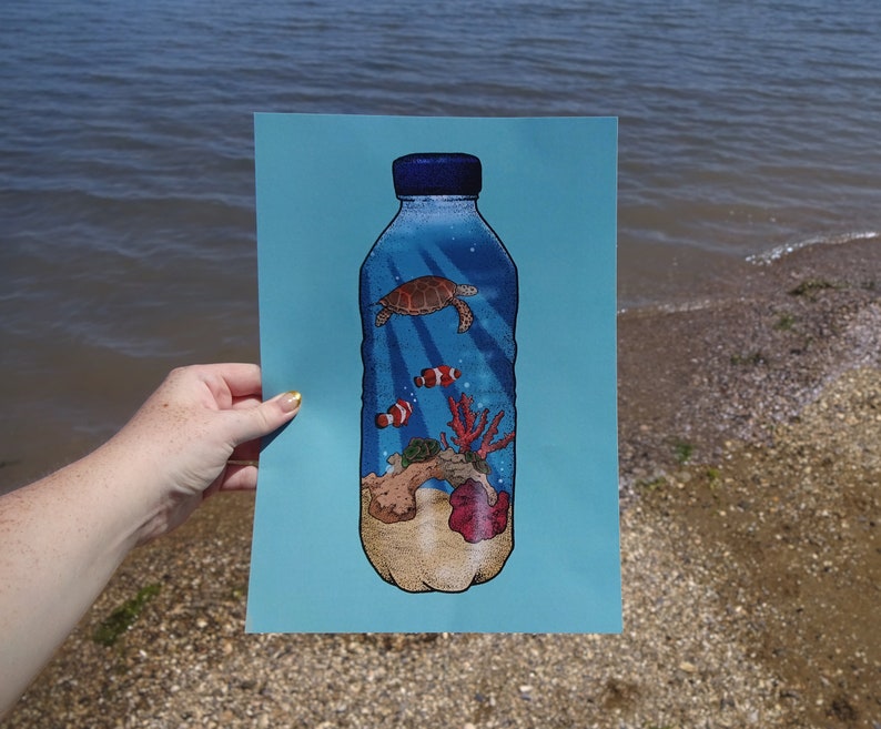 May include: A blue plastic bottle with a sea turtle, coral, and fish inside. The bottle is on a blue background.