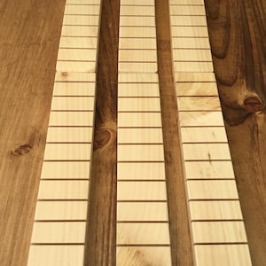 May include: Three wooden strips with evenly spaced grooves, likely for use in a craft project or as a decorative element.