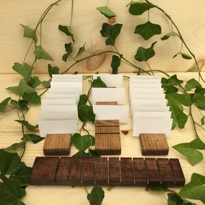 May include: A set of 10 wooden card holders with white cards. The holders are arranged in two rows, with a wooden base in the front. The holders are surrounded by green ivy.
