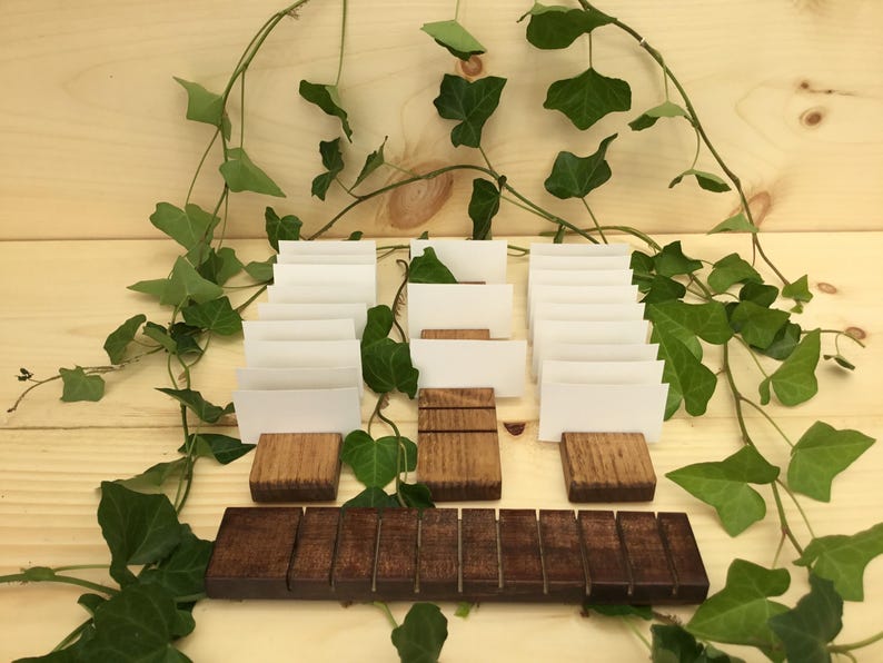 May include: A set of 10 wooden card holders with white cards. The holders are arranged in two rows, with a wooden base in the front. The holders are surrounded by green ivy.