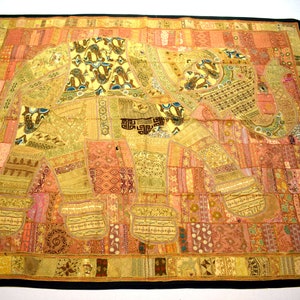 May include: A colorful patchwork tapestry featuring an embroidered elephant design in shades of gold, pink, and brown. The elephant is made up of various fabric scraps sewn together, creating a unique and textured look.