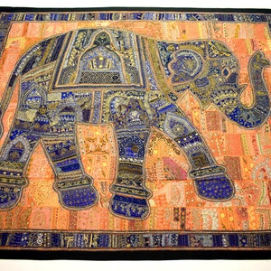 May include: A colourful patchwork tapestry featuring a large blue and gold elephant with intricate details. The elephant is set against a background of peach and orange fabric with a black border.