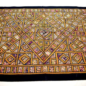 May include: A large, square, black and gold tapestry with a geometric pattern. The tapestry is made of many different fabrics and colors, including red, blue, purple, and white. The pattern is intricate and detailed, and the tapestry is a beautiful example of traditional Indian craftsmanship.