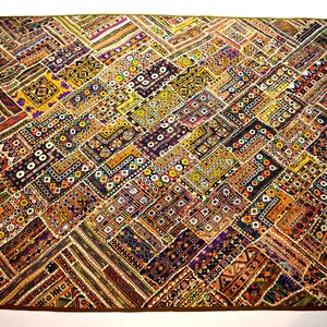 May include: A colorful patchwork quilt with a geometric pattern. The quilt is made of various fabrics in shades of brown, yellow, orange, red, blue, and green. The quilt is decorated with small beads and sequins.