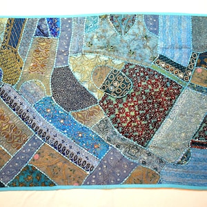 May include: A patchwork quilt with a blue, brown, and gold design. The quilt is made of different fabrics and is decorated with beads and sequins.