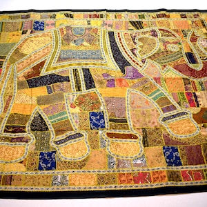 May include: A colorful patchwork quilt featuring an elephant design. The quilt is made of various fabrics in shades of brown, gold, purple, and blue. The elephant is outlined in gold thread and has intricate details.