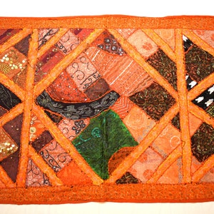 May include: A patchwork quilt with a geometric design in shades of orange, brown, green, and pink. The quilt is made of various fabrics and textures, including velvet, silk, and cotton. The quilt is decorated with sequins and beads.