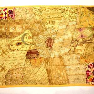 May include: A patchwork quilt with a yellow background and various patterns in shades of brown, gold, and pink. The quilt is made of different fabrics and has a beaded border.