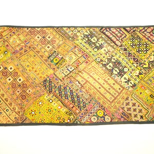 May include: A colorful patchwork quilt with a variety of geometric patterns and embroidered details. The quilt is made of different fabrics in shades of yellow, orange, red, blue, green, and purple. The quilt is edged with a dark gray border.