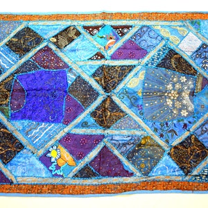 May include: A patchwork quilt with a blue background and various coloured fabric squares. The quilt is decorated with sequins and embroidery.