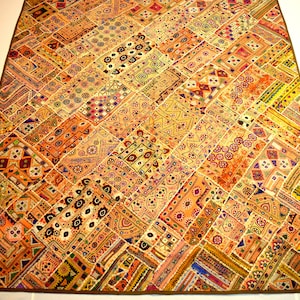 May include: A colorful patchwork quilt with intricate embroidery and mirror accents. The quilt is made of various fabrics in shades of orange, yellow, pink, and brown.