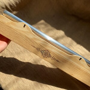 May include: A wooden box with a silver metal bar inside. The box has a geometric design burned into the wood.